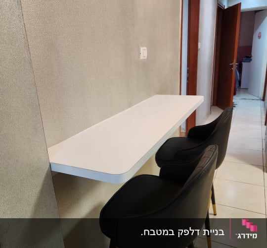 דלפק לבן עם שני כיסאות בר שחורים במטבח